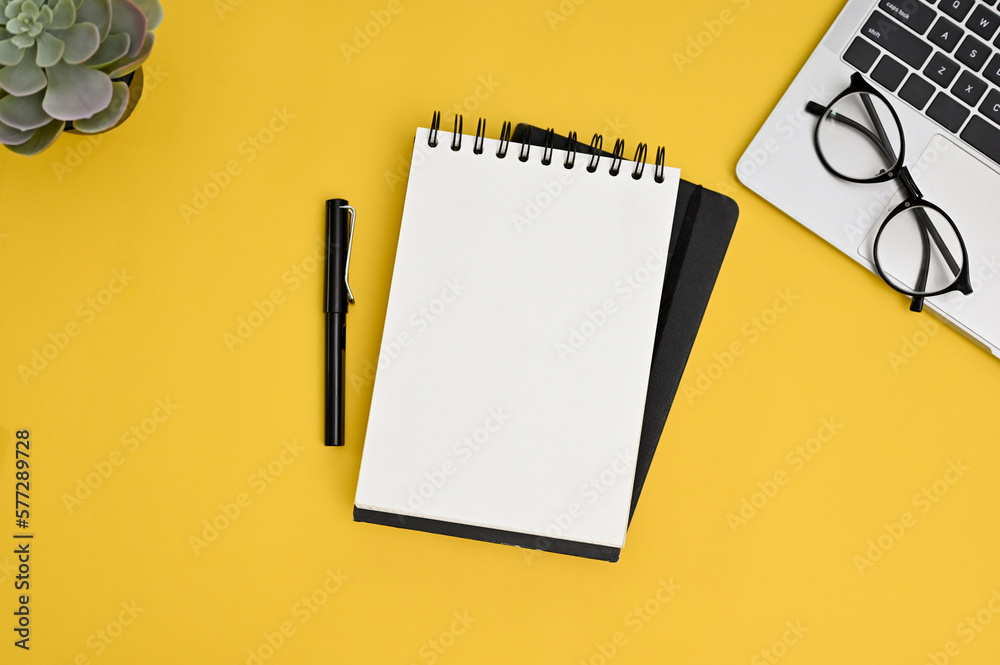Creative yellow workspace background with empty page of notepad, decor and laptop. top view Creative yellow workspace background with empty page of notepad, decor and laptop. top view