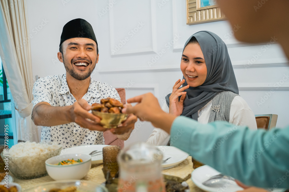 husband gives food and invites guests to break the fast at the dining table husband gives food and invites guests to break the fast at the dining table