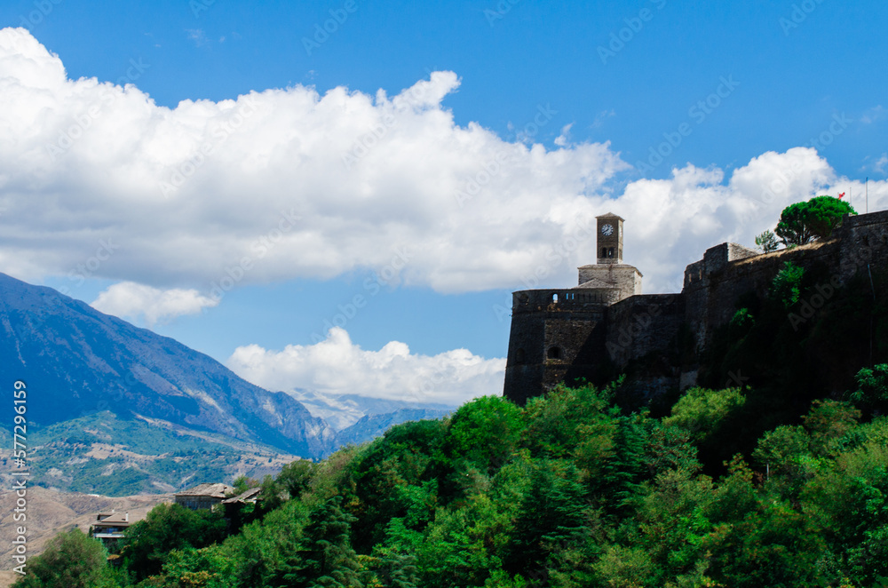 Beautiful panorama of Gjirokaster fortress among green trees and clouds, stock photo
