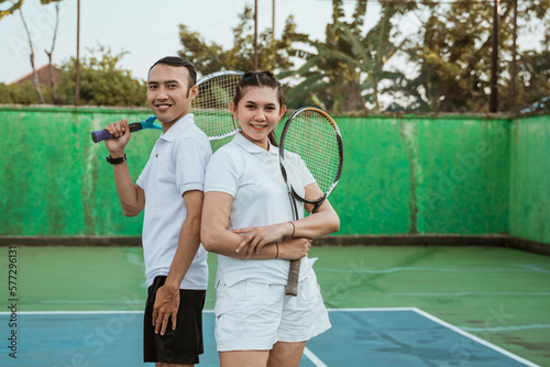 asian tennis athletes smiling while standing back to back on tennis court