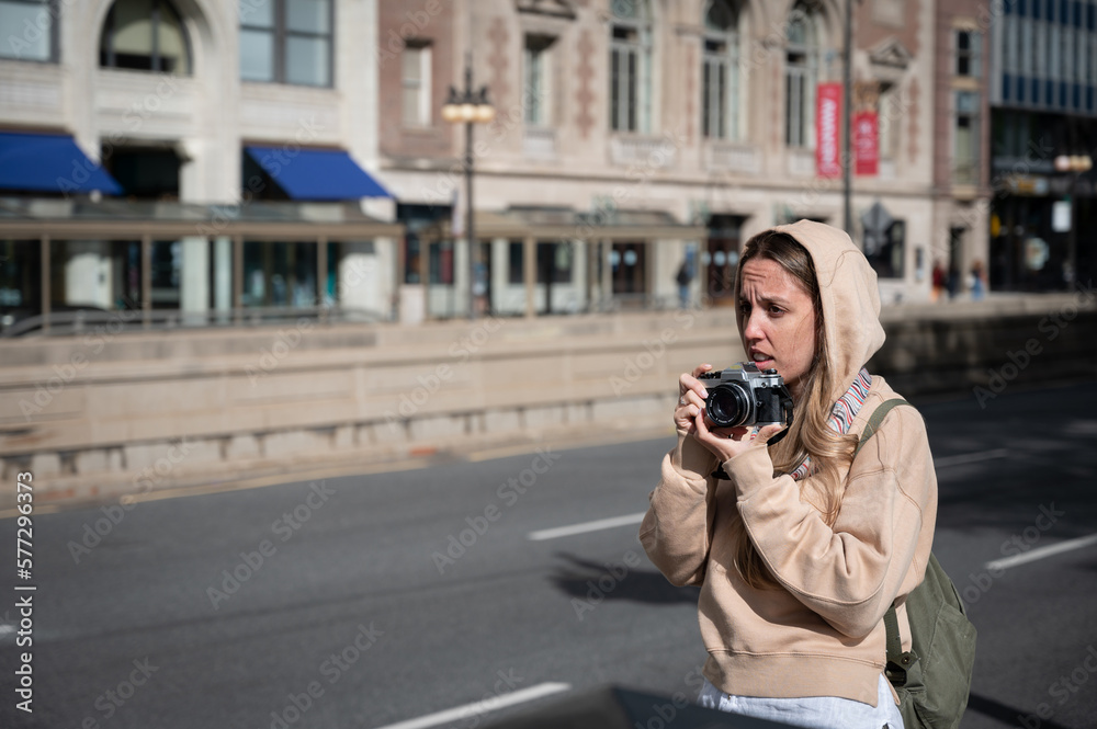 Young tourist girl in the American city of Chicago taking photos with an old classic reel photo camera