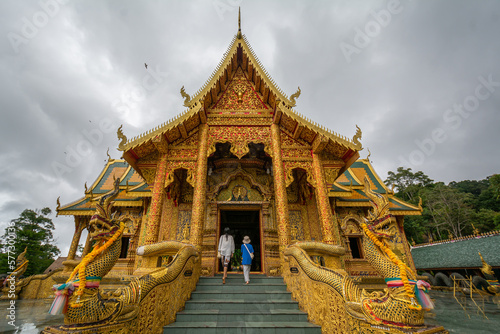 The young girl traveler with the golden temple in the back at Wat Phraphutthabat Si Roi, Chiang Mai, Thailand photo