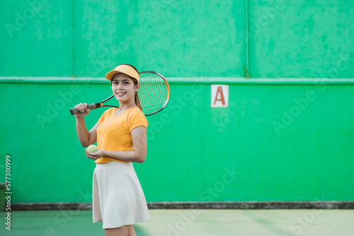 smiling tennis player carrying racket and ball on green screen background © Odua Images