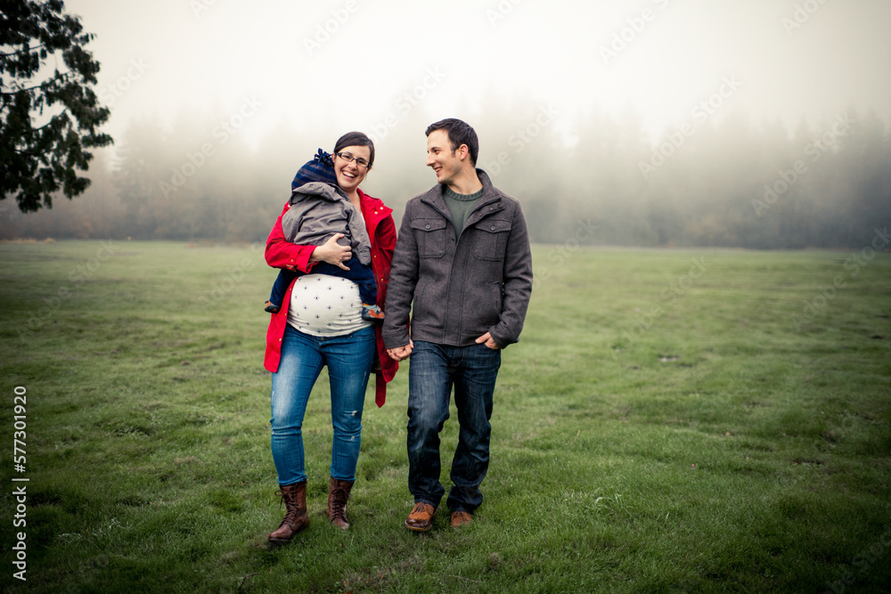 A pregnant mother holds her son while sharing a laugh with her husband at a local park. A pregnant mother holds her son while sharing a laugh with her husband at a local park.