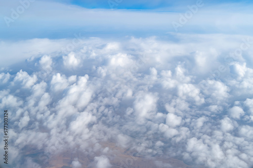 Fototapeta Naklejka Na Ścianę i Meble -  Wing of an airplane jet flying above clouds with blue sky from the window in traveling and transportation concept. Nature landscape background.