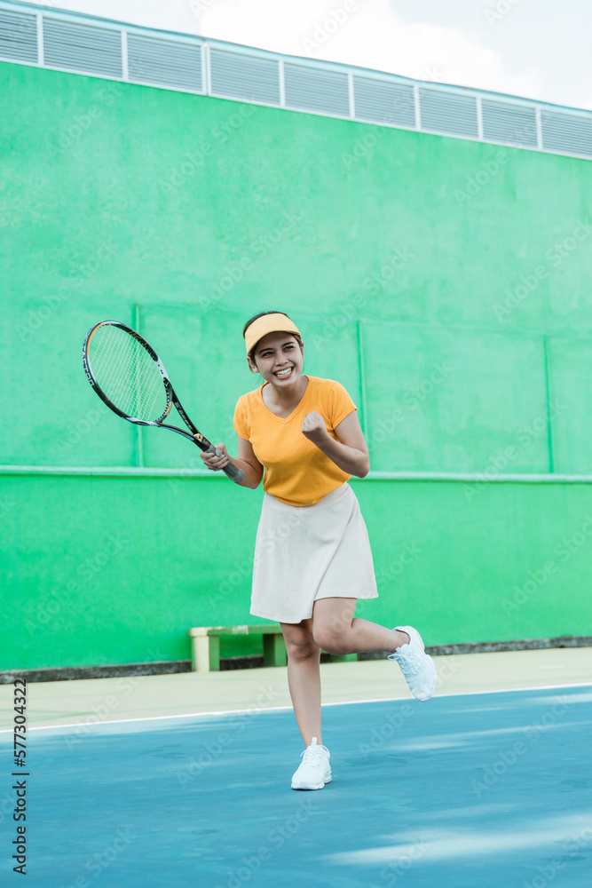 female excited tennis player after hitting the ball to score with racket on tennis court