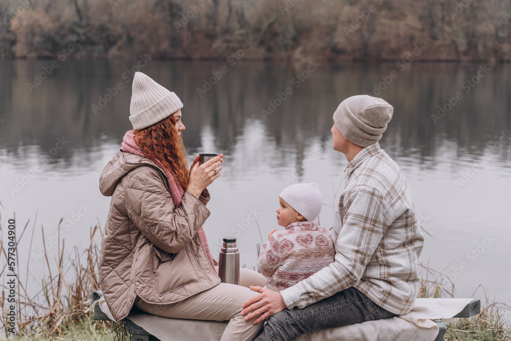 Parents and a little girl are relaxing in a spring park near the river Parents and a little girl are relaxing in a spring park near the river
