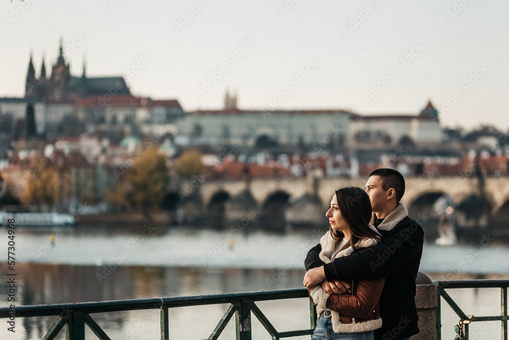 man and woman hugging near river and bridge in center of Prague man and woman hugging near river and bridge in center of Prague