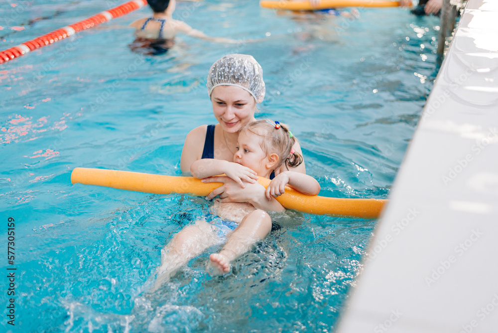 Two year baby girl at his first swimming lesson wiht mother