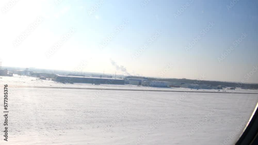 The beginning of the takeoff of the aircraft from the runway in winter. View from the plane to the snowy airfield. The beginning of the takeoff of the aircraft from the runway in winter. View from the plane to the snowy airfield.