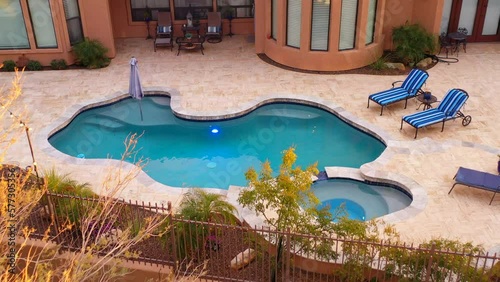 A desert landscaped backyard located in Arizona featuring
a travertine tiled pool deck outdoors kitchen and fireplace.