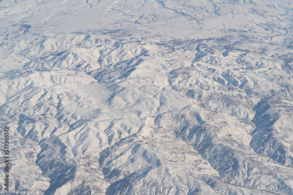 Wing of aerial view of an airplane jet flying above clouds from the window in traveling and transportation concept. White snow mountain in winter season. Nature landscape background. Wing of aerial view of an airplane jet flying above clouds from the window in traveling and transportation concept. White snow mountain in winter season. Nature landscape background.