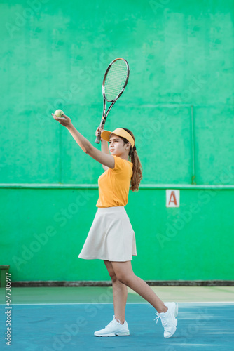 female tennis player serving the ball with a racket on the tennis court © Odua Images