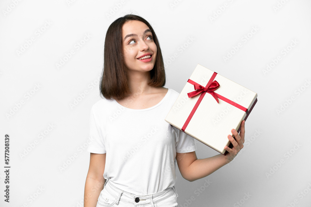 Young Ukrainian woman holding a gift isolated on white background looking up while smiling Young Ukrainian woman holding a gift isolated on white background looking up while smiling