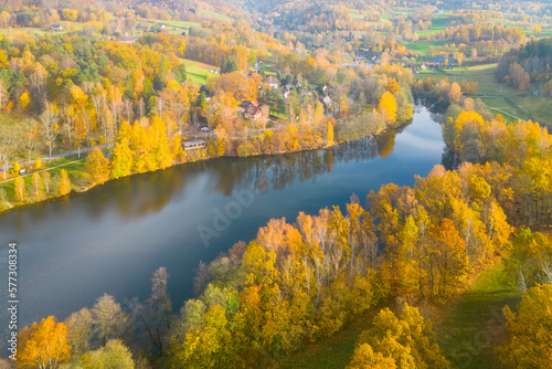 Fojtka water reservoir surrounded by vibrant colored forest at autumn time. Aerial view from drone.