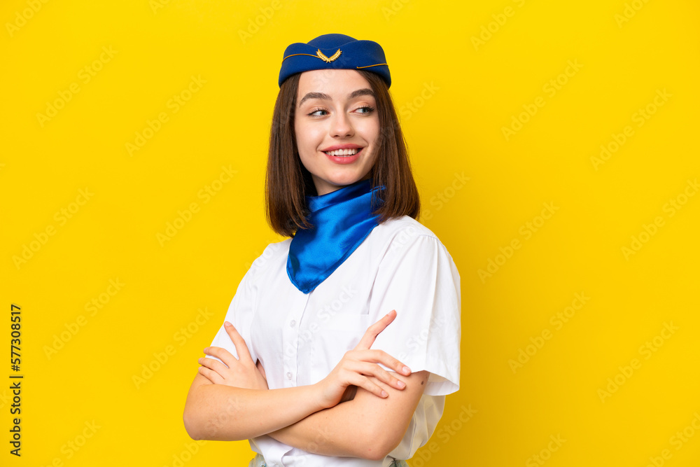Airplane stewardess Ukrainian woman isolated on yellow background with arms crossed and happy Airplane stewardess Ukrainian woman isolated on yellow background with arms crossed and happy