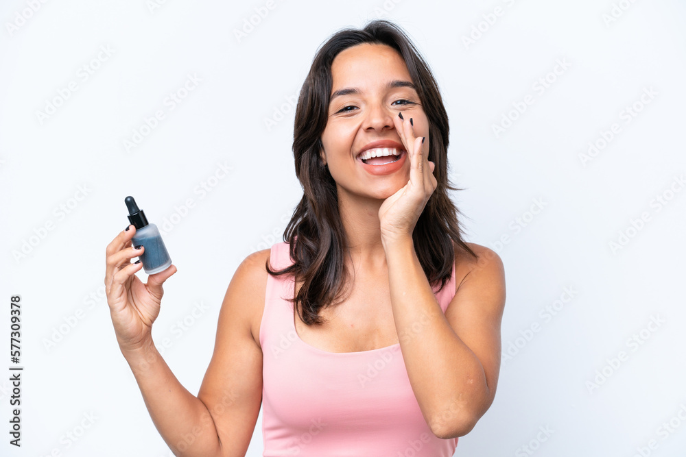 Young hispanic woman holding serum isolated on white background shouting with mouth wide open Young hispanic woman holding serum isolated on white background shouting with mouth wide open