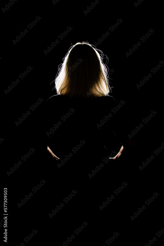 Woman in front of a light source in a black room, only the outlines can ...