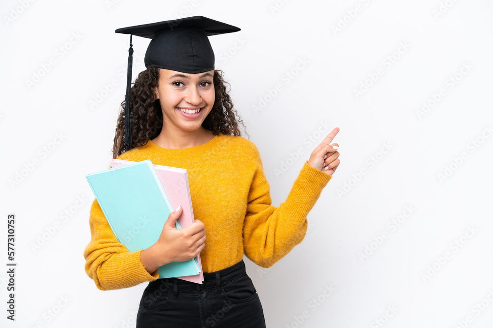 Arab university graduate woman holding books isolated on white background pointing finger to the side Arab university graduate woman holding books isolated on white background pointing finger to the side