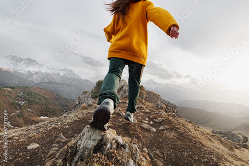 Foto Sporty young girl runs high in mountains. Active tourism concept