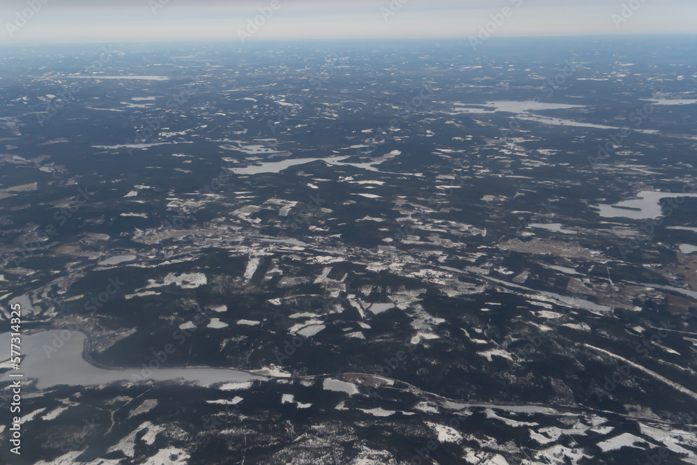 Wing of aerial view of an airplane jet flying above clouds from the window in traveling and transportation concept. White snow mountain in winter season. Nature landscape background.