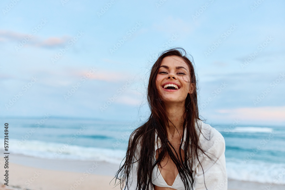 Woman smile and happiness walking on the beach and having fun smile with teeth in the background of the ocean, vacation summer trip, sunset on the beach island of Bali Woman smile and happiness walking on the beach and having fun smile with teeth in the background of the ocean, vacation summer trip, sunset on the beach island of Bali