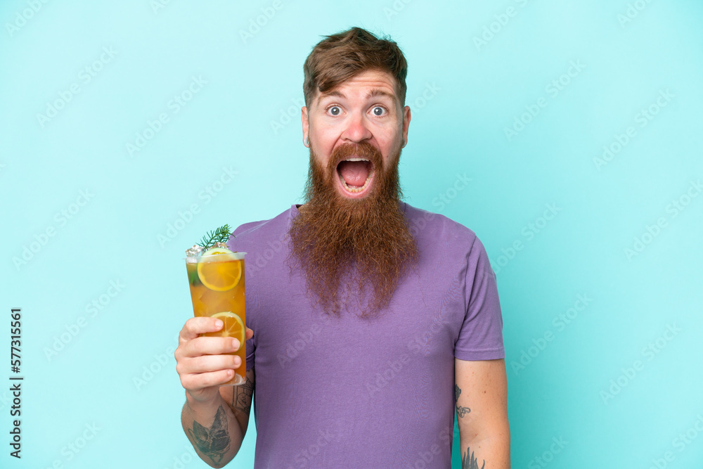 Redhead man with long beard holding a cocktail isolated on blue background with surprise and shocked facial expression Redhead man with long beard holding a cocktail isolated on blue background with surprise and shocked facial expression