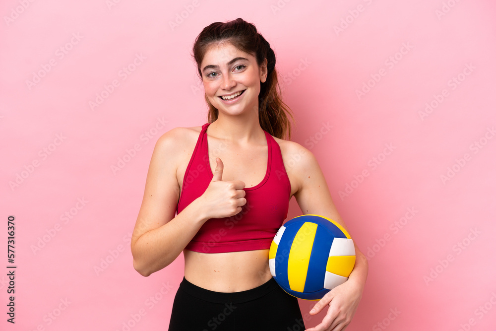 Young caucasian woman playing volleyball isolated on pink background giving a thumbs up gesture