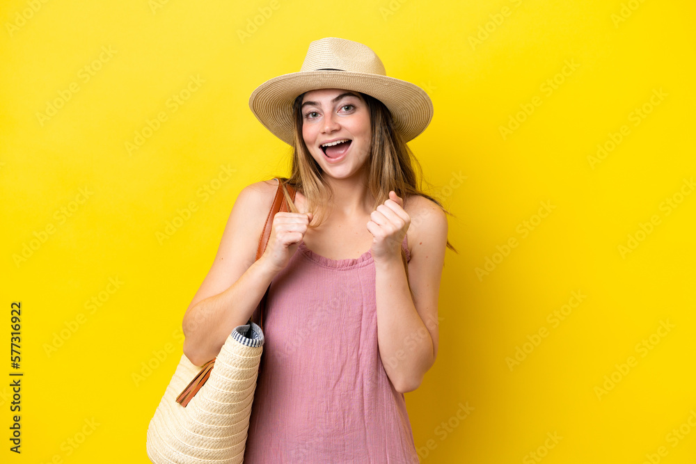 Young caucasian woman holding a beach bag isolated on yellow background celebrating a victory in winner position Young caucasian woman holding a beach bag isolated on yellow background celebrating a victory in winner position