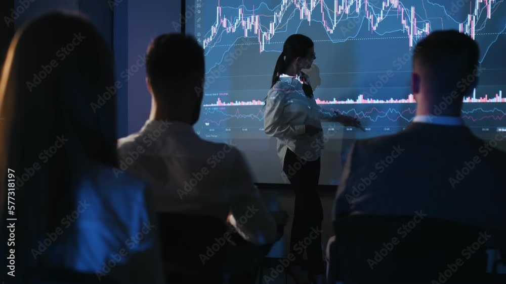 Woman in formal clothes is showing business plan on the big projector for the people that sitting and listening Woman in formal clothes is showing business plan on the big projector for the people that sitting and listening