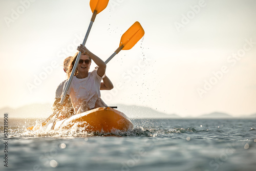 Fotografia Young couple walks on sea kayak or canoe at calm sunset sea