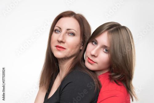 Portrait of woman mother and daughter looking at camera. Mom in black t-shirt and teenager in red t-shirt. Studio shot on white background. Part of photo series