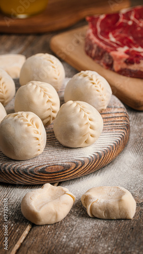Semi-finished manti oriental dumplings on wooden board with flour