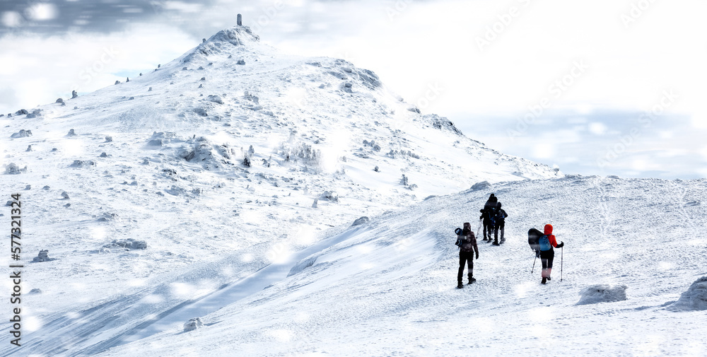 Group of people traveling through snow-covered winter Carpathian mountains.
