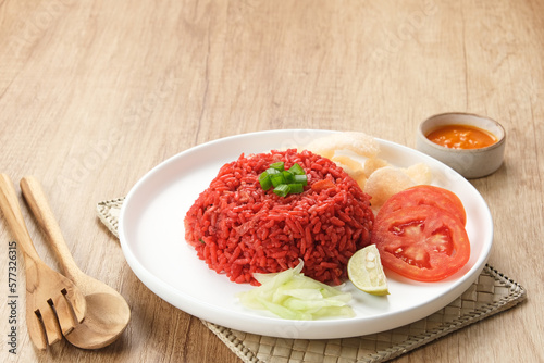 Nasi Goreng Merah, traditional food from Makassar, Indonesia. Fried rice with tomato sauce, shrimp, meatballs and egg. Served with pickled cucumber, chili sauce and lime 