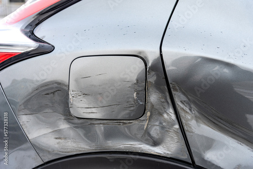 Silver car after the accident  broken door  fender and fuel tank close-up. Car accident close-up. A close-up of damage to the rear fender  door and fuel tank of a silver car.