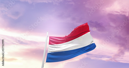 Waving Flag of Netherlands in Blue Sky. The symbol of the state on wavy cotton fabric.