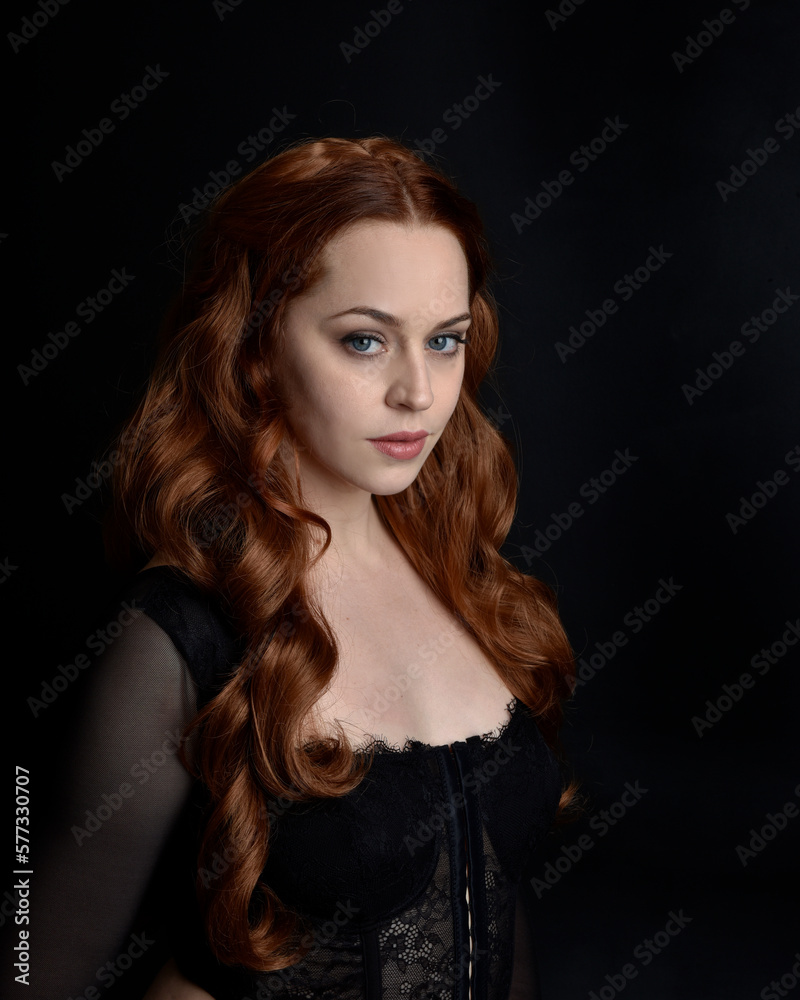 close up portrait of beautiful woman with long red hair wearing sheer corset top. variety of facial expressions, Isolated on dark studio background with moody silhouette lighting. close up portrait of beautiful woman with long red hair wearing sheer corset top. variety of facial expressions, Isolated on dark studio background with moody silhouette lighting.