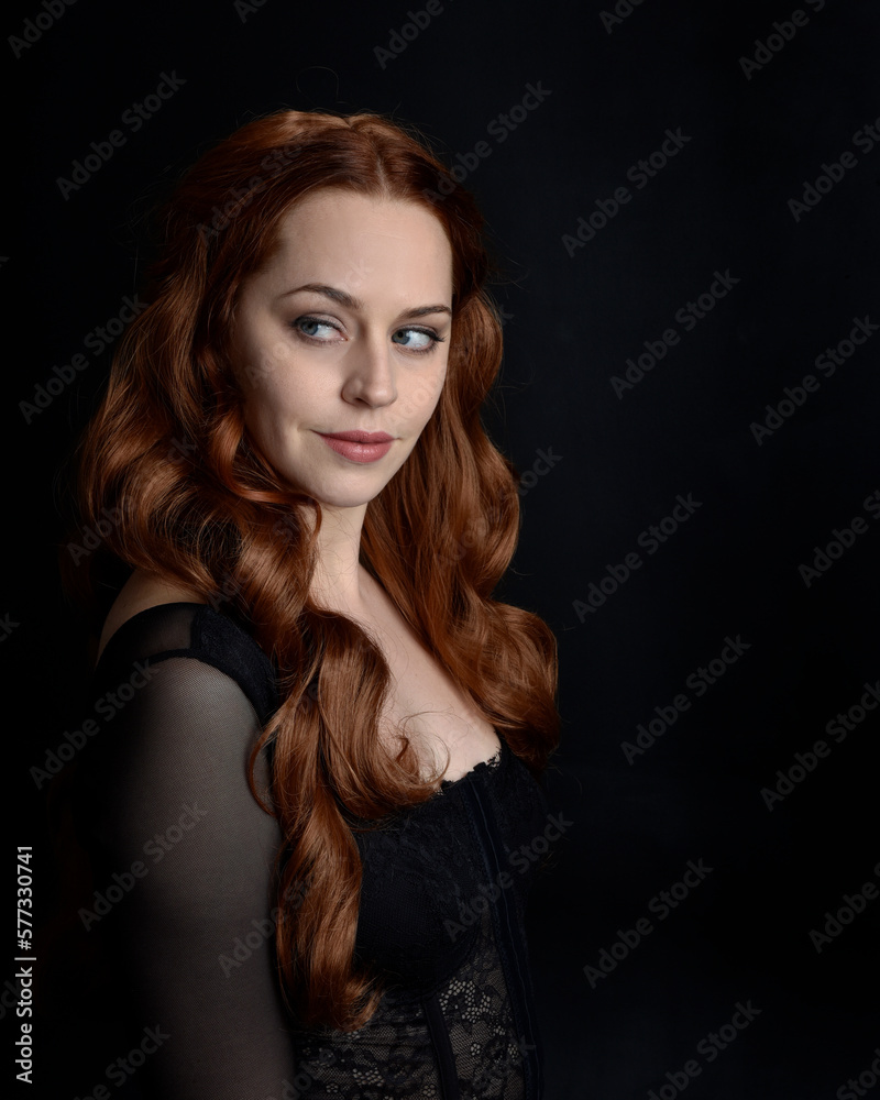 close up portrait of beautiful woman with long red hair wearing sheer corset top. variety of facial expressions, Isolated on dark studio background with moody silhouette lighting. close up portrait of beautiful woman with long red hair wearing sheer corset top. variety of facial expressions, Isolated on dark studio background with moody silhouette lighting.