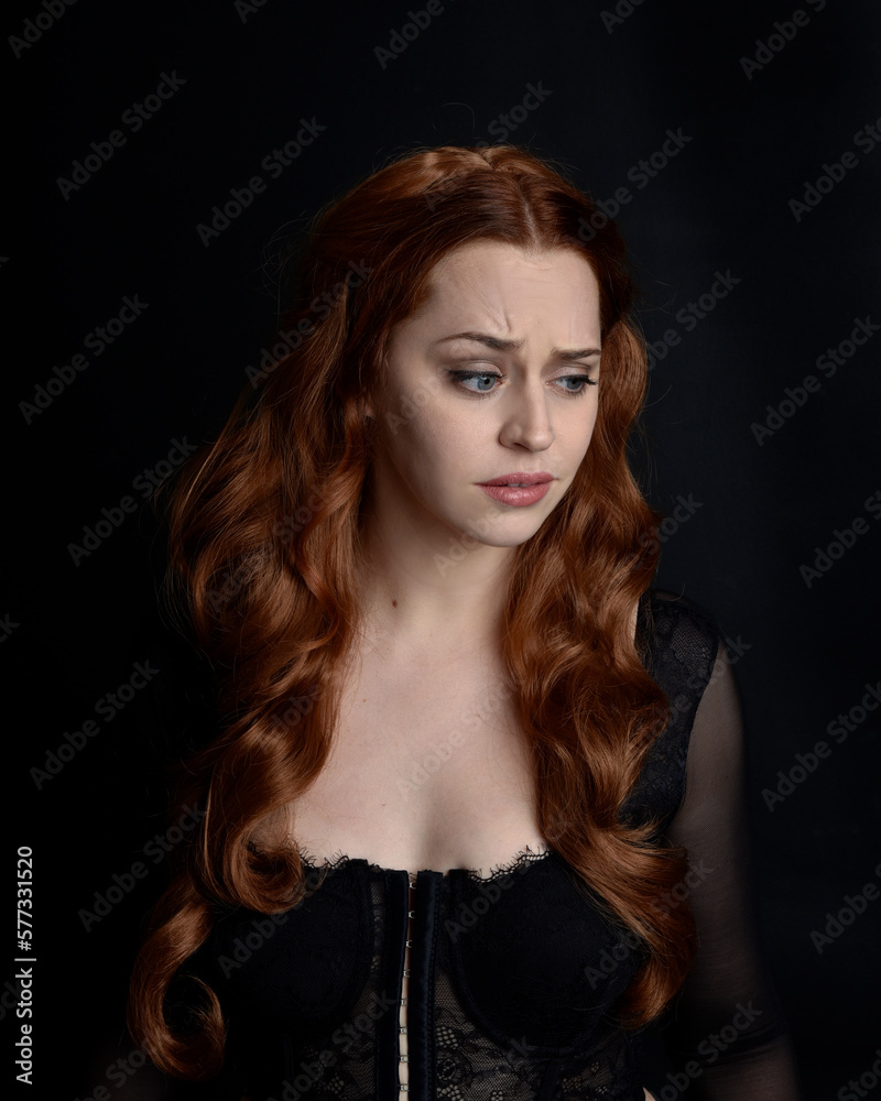 close up portrait of beautiful woman with long red hair wearing sheer corset top. variety of facial expressions, Isolated on dark studio background with moody silhouette lighting. close up portrait of beautiful woman with long red hair wearing sheer corset top. variety of facial expressions, Isolated on dark studio background with moody silhouette lighting.