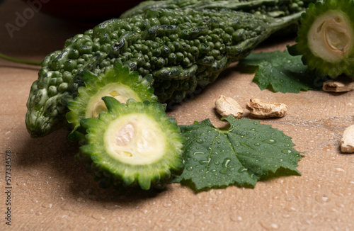 Closeup of fresh bitter gourd with cut slice isolated on wooden background. photo