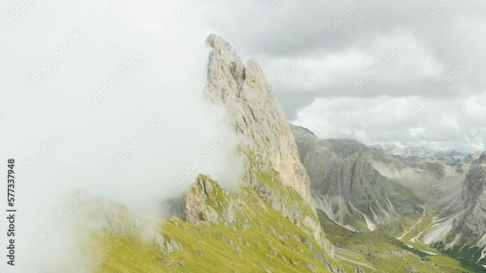 Dense fog covered rocky peak of Seceda mountain in touristic Italian Alps. Observation point overlooking ridgeline on cloudy day aerial view