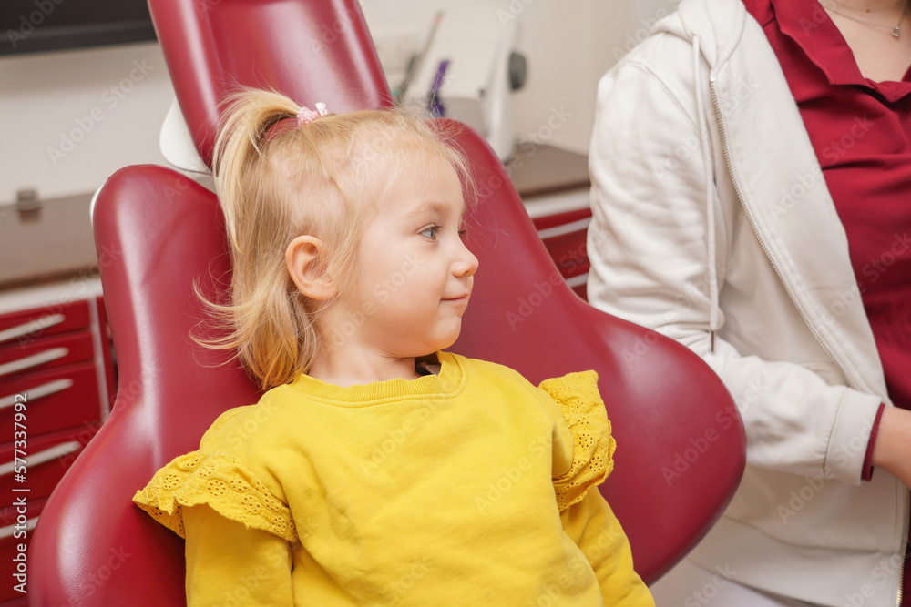 little-joyful-girl-sits-on-a-dental-chair-after-dental-treatment-stock