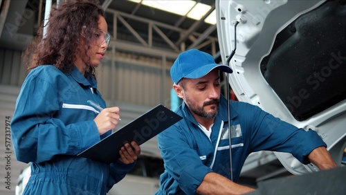 Two Auto mechanic checking car engine oil in car auto repair service center. Car repair and maintenance. Car mechanic working at automotive service center