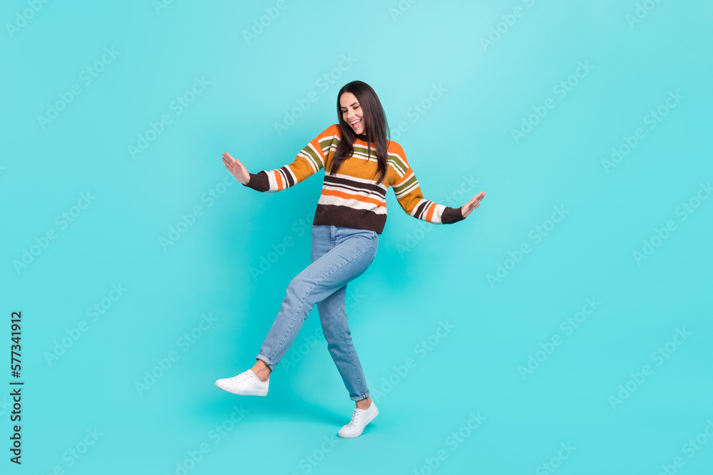 Full length photo of funky cheerful woman wear striped sweater smiling having fun isolated turquoise color background Full length photo of funky cheerful woman wear striped sweater smiling having fun isolated turquoise color background