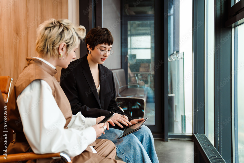 Fototapeta premium Two businesswoman working on tablet together during meeting in office