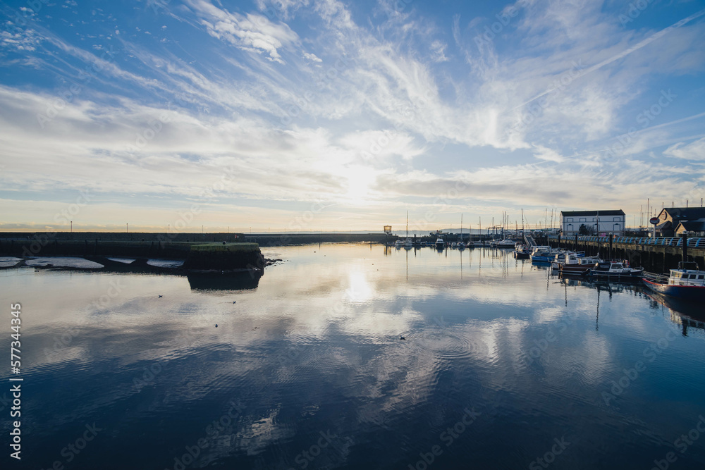 Carrickfergus, Northern Ireland, wide angle lens with sunrise, blue sky, water reflections and horizon, close to Carrickfergus castle