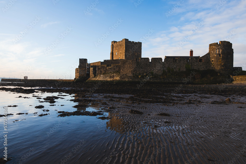 Silhouette of Carrickfergus Castle, Northern Ireland, wide angle lens with sunrise, blue sky, water reflections and horizon