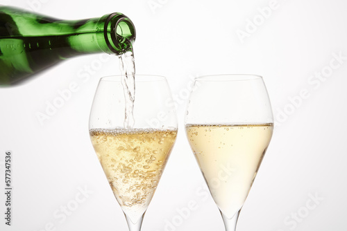 Sparkling wine pours from green bottleneck, creates bubbles.