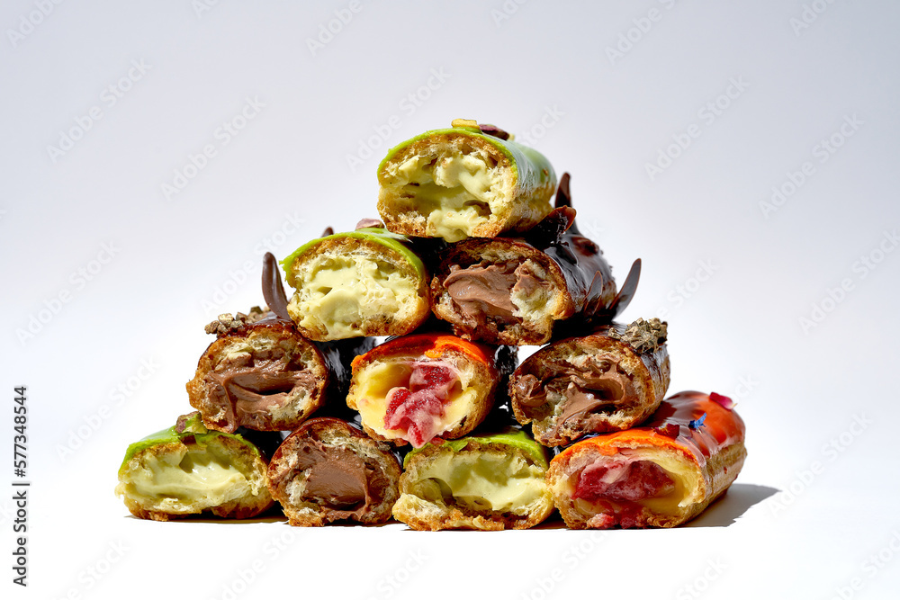 Set of different eclairs with different flavors cut in half. White background